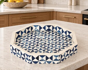 May include: An octagonal serving tray featuring a geometric pattern of alternating dark blue and white triangles. The tray has a raised white border and a flat base, showcasing a repeating mosaic-style design across the interior and exterior sides.