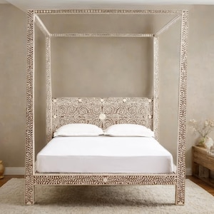 May include: A four-poster bed with a white and brown floral design. The bed frame and headboard feature intricate patterns. The bed is made up with white sheets and pillows. The bed is on a white rug.