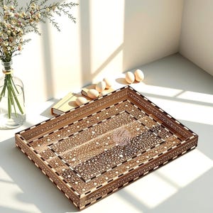 May include: A rectangular wooden tray with intricate floral and geometric inlay patterns. The tray features a light brown and dark brown color scheme with white accents. The design is symmetrical and detailed, suitable for serving or display.