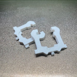 Peut inclure: Deux clips en plastique blanc, chacun avec une forme et un design uniques. Les clips sont conçus pour maintenir des objets ensemble ou les fixer en place.