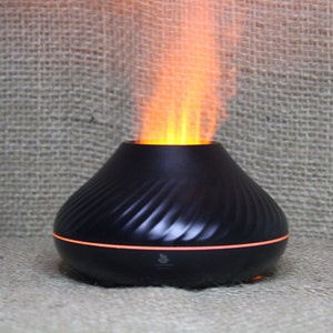 Può includere: Diffusore di oli essenziali nero con effetto fiamma. Il diffusore ha un design a spirale e una luce arancione attorno alla base. L'effetto fiamma emette una luce arancione, creando un'atmosfera calda. Progettato per l'aromaterapia.