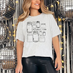 May include: A gray t-shirt with a graphic of jars and the text "Actually, I can".