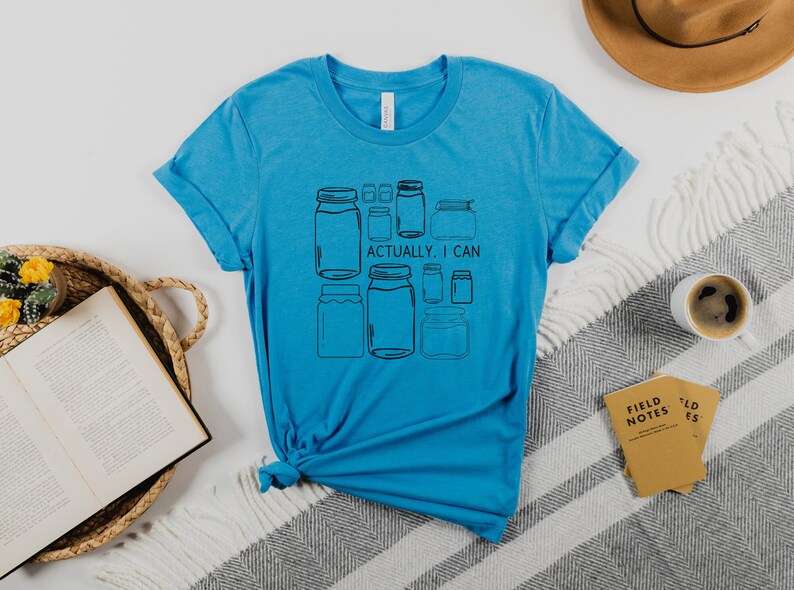 May include: A turquoise blue t-shirt with a graphic of jars and the text "Actually, I can".