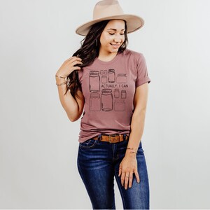 May include: A mauve t-shirt with a graphic of jars and the text "Actually, I can".