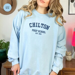 May include: Light blue sweatshirt with the text "Chilton Prep School Est. 1803" in navy blue.