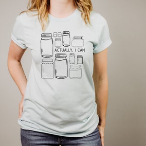 May include: A light blue t-shirt with a graphic of various jars and the text "Actually, I can".