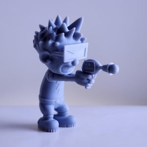 Puede incluir: Una figurita azul impresa en 3D de un personaje con el pelo de punta, que lleva gafas protectoras y sostiene una pistola futurista.