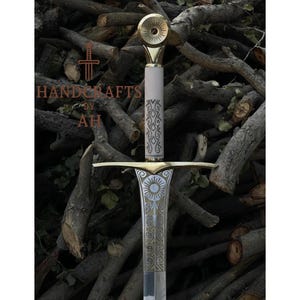 Könnte beinhalten: Ein detailliertes, handgefertigtes Schwert. Der Griff ist weiß mit einem verzierten Muster, und der Parierstange und der Knauf sind goldfarben. Die Klinge ist silberfarben mit geätzten Details. Der Text "HANDCRAFTS BY AH" ist sichtbar.