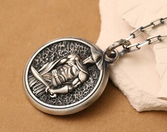 May include: Silver pendant necklace featuring a detailed, circular design of a warrior holding a sword. The pendant is attached to a silver chain.