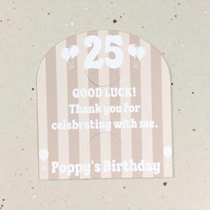 May include: A beige and white striped birthday card with the number 25 in white. The card includes the text "GOOD LUCK! Thank you for celebrating with me. Poppy's Birthday" and white balloon graphics.