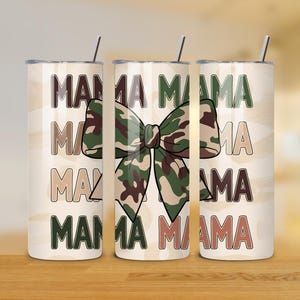 May include: Three stainless steel tumblers with lids and straws. The tumblers are white with a camouflage bow and the text "Mama" repeated on each tumbler.