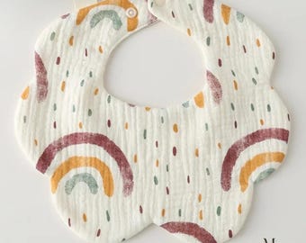 Può includere: Bavaglino bianco per neonati con bordo smerlato, decorato con motivi arcobaleno e puntini colorati. Il bavaglino ha una chiusura a scatto sul collo ed è realizzato in un tessuto morbido e strutturato. Il design include sfumature di rosso, giallo e verde.