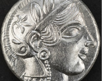 May include: Silver coin with a profile of a woman wearing a crown and a necklace. The coin has a floral design around the edge.
