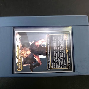 May include: A blue card holder containing a Final Fantasy trading card. The card features an illustration of Cloud, with the text "Cloud, Ex-SOLDIER" and game details. The card has a power rating of 4/4.