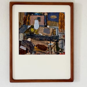 Könnte beinhalten: Ein gerahmtes abstraktes Gemälde mit einer dunklen, texturierten Innenszene, einer weißen Vase, gelben Kugeln sowie gedeckten Blau-, Braun- und Grautönen. Das Kunstwerk befindet sich in einem glatten Holzrahmen mit einem breiten, cremeweißen Passepartout.