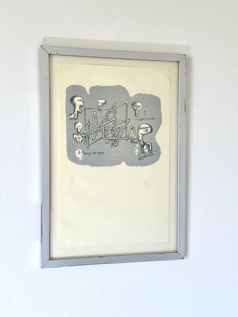 K&ouml;nnte beinhalten: Ein gerahmter Druck mit einer grauen abstrakten Form, die schwarze Strichzeichnungen von drei Figuren und eine komplexe geometrische Struktur enth&auml;lt. Der Text "Juegos de mesa" und "...y pedetto" ist im grauen Bereich sichtbar, mit einer Signatur und Nummerierung am unteren Rand.