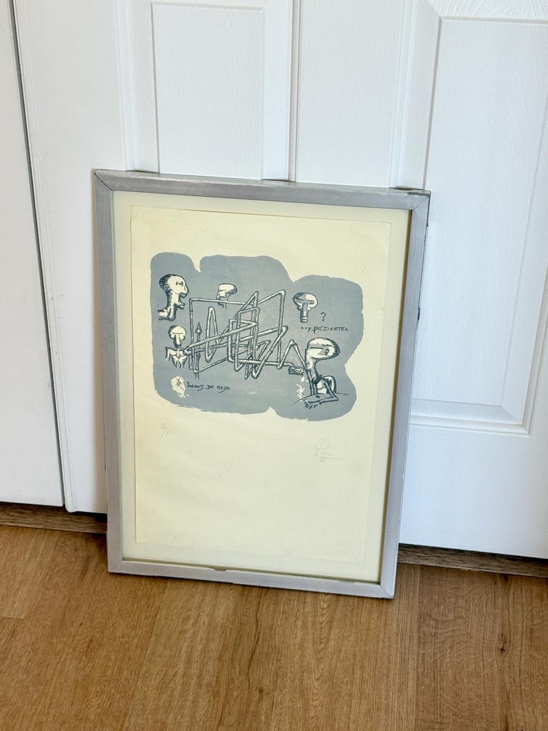 K&ouml;nnte beinhalten: Ein gerahmter Druck mit einer surrealen Illustration auf cremefarbenem Hintergrund. Eine graue Form enth&auml;lt schwarze Strichzeichnungen abstrakter Figuren und komplexer geometrischer Rohre. Der Text "...y paciente" und "Lunes de ocio" ist sichtbar.
