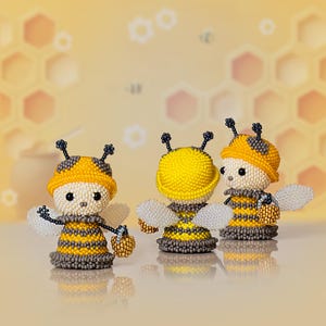 Three cartoon-style beaded bees in yellow hats stand together, showcasing the cute beaded bee pattern created in Peyote Stitch.