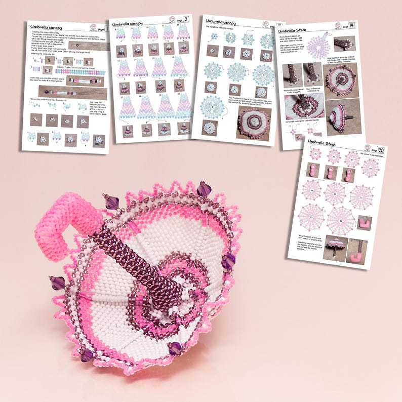 White and pink beaded umbrella in peyote stitch lying on its dome beside printed sheets with example patterns.
