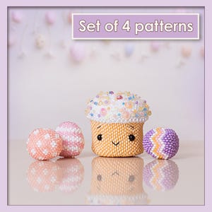 May include: A set of four beaded patterns, including a cupcake and three decorative balls. The cupcake is yellow with a white beaded top and a smiling face. The balls are pink, white, and purple, with various patterns. The text "Set of 4 patterns" is at the top.