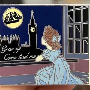 Könnte beinhalten: Eine blaue Emaille-Anstecknadel mit einem Mädchen in einem blauen Kleid, das aus einem Fenster auf ein Schiff schaut, das unter einem Vollmond davonsegelt. Der Text "Grow up Come find me" steht unter dem Fenster.