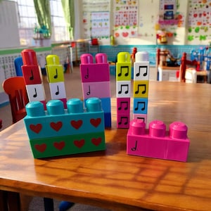 May include: A set of colorful plastic building blocks with musical notes printed on them. The blocks are arranged in different patterns and heights, creating a playful and educational activity.
