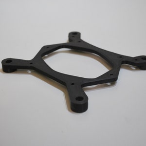 Op de afbeelding: Zwarte plastic CPU-koeler montagebeugel met zes gaten voor schroeven.