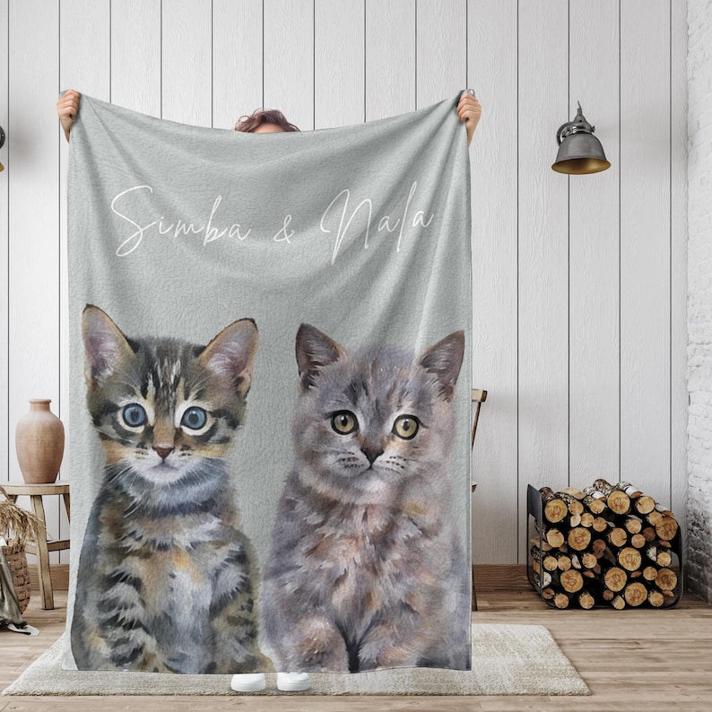 May include: A gray fleece blanket with the text "Simba & Nala" printed in white. Two cats, one tabby and one gray, are pictured on the blanket.