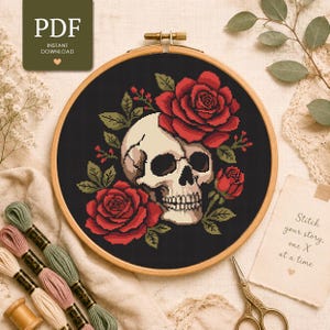 May include: A cross stitch pattern featuring a human skull surrounded by red roses and green leaves on a black background, displayed in a wooden embroidery hoop. The image includes a PDF instant download label and a note with the text Stitch your story, one X at a time.