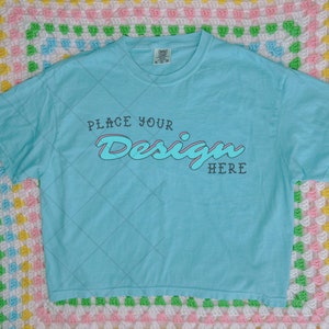 May include: A light blue t-shirt with a white graphic that says "Place Your Design Here" in a retro font.