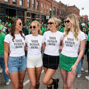 Puede incluir: Cuatro personas con camisetas blancas con el texto "YOUR DESIGN HERE" en fuente gótica negra, combinadas con shorts de mezclilla, una falda negra y una falda verde. Llevan gafas de sol y sonríen, de pie en una calle.