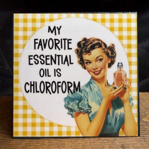 May include: A square decorative sign with a yellow and white gingham border. The center features a white circle with the text MY FAVORITE ESSENTIAL OIL IS CHLOROFORM and an illustration of a person in a blue dress holding a small glass bottle.