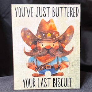 May include: A cartoon cowboy with a starry hat and a big mustache says "You've just buttered your last biscuit".