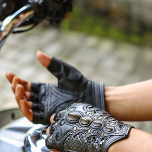 May include: A pair of black leather fingerless gloves with decorative stitching and metal accents. The gloves have a zipper on the wrist.