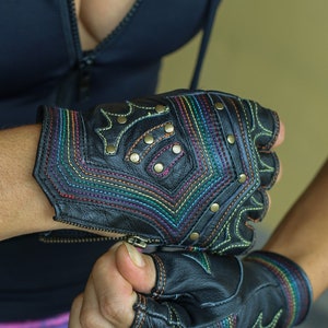 May include: A pair of black leather fingerless gloves with colorful stitching and metal studs. The gloves have a rainbow pattern on the back of the hand.