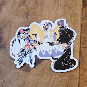 Puede incluir: Una pegatina troquelada con tres personajes de dibujos animados. Uno lleva un disfraz de bufón, otro es un ángel y el tercero es una figura alta y delgada con un atuendo negro. Los personajes se señalan entre sí.