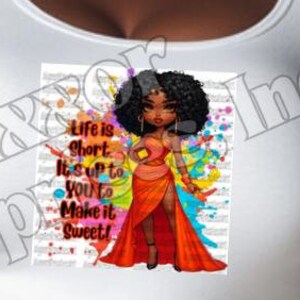 Può includere: Una maglietta bianca con una grafica colorata di una donna in un vestito rosso. La grafica include il testo "Life is short. It's up to you to make it sweet!"