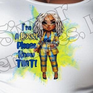 Può includere: Maglietta bianca con un'illustrazione di cartone animato di una donna in un abito a quadri giallo e blu. Il testo "I'm a Boss! Please Know That!" è stampato sulla maglietta.