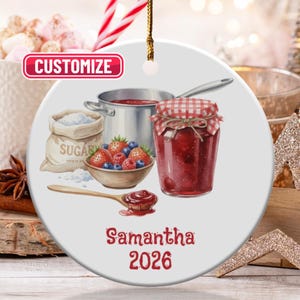 May include: A round ceramic ornament featuring a watercolor illustration of jam-making. It includes a pot, a jar of jam, a bowl of berries, and a bag of sugar. The ornament has the word "CUSTOMIZE" and the name "Samantha 2026".