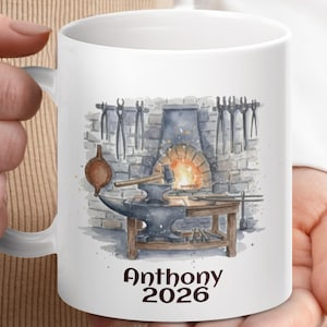 Pode incluir: Caneca de cerâmica branca com uma ilustração em aquarela de uma forja de ferreiro, com um fogo brilhante, uma bigorna e ferramentas. A caneca tem o nome "Anthony" e o ano "2026" impressos. Um ótimo presente para um ferreiro ou metalúrgico.