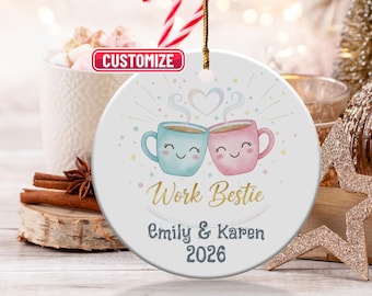 May include: A white ceramic ornament with a gold string features two smiling coffee mugs, one blue and one pink, with the text "Work Bestie", names, and the year 2026. The word "Customize" is in a red box.