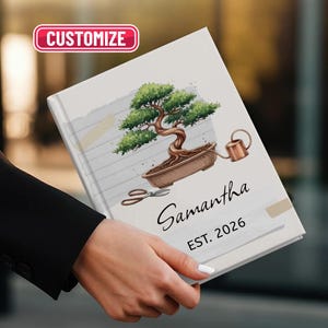 May include: A personalized notebook featuring a bonsai tree illustration, watering can, and scissors. The cover includes the name "Samantha" and the year "EST. 2026". The notebook has a "Customize" button.