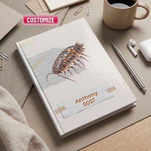 May include: A hardcover journal featuring a realistic illustration of a brown woodlouse on a light gray background. The cover includes a white paper strip with the text Anthony 2027 and a red rectangular button with the text CUSTOMIZE.