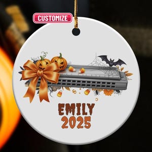May include: A white ceramic Halloween ornament featuring a harmonica, pumpkins, and a bow. The ornament includes the text "EMILY 2025" and a "Customize" label. A bat, spiderweb, and candy corn are also featured.