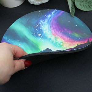 Pu&ograve; includere: Un tappetino per mouse rotondo con un design colorato di aurora boreale. Il tappetino ha un retro in gomma nera.