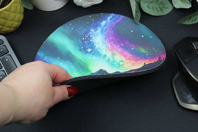 Pu&ograve; includere: Un tappetino per mouse rotondo con un design colorato di aurora boreale. Il tappetino ha un retro in gomma nera.