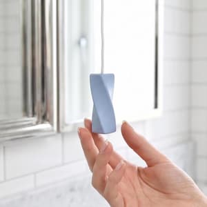 Peut inclure: Une poignée de tirage de lumière géométrique torsadée bleu clair attachée à un cordon blanc. L'objet présente une finition lisse et mate avec un design en spirale distinct qui se rétrécit légèrement vers le haut et le bas, suspendu par une fine ficelle blanche.