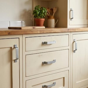 Puede incluir: Una taza de cerámica blanca con un asa negra y el texto "But First, Coffee" en negro, con una fuente de estilo manuscrito. La taza está sobre una superficie blanca.