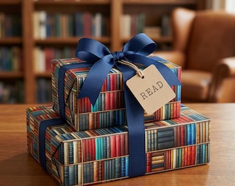 Pode incluir: Duas caixas de presente retangulares empilhadas, embrulhadas em papel com um padrão de estante de livros colorida. Uma fita azul escura está amarrada em um laço ao redor das caixas, com uma etiqueta quadrada marrom clara com a palavra READ.