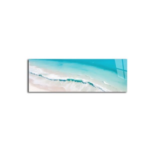 May include: An aerial view of a turquoise ocean with white waves crashing on a sandy beach.